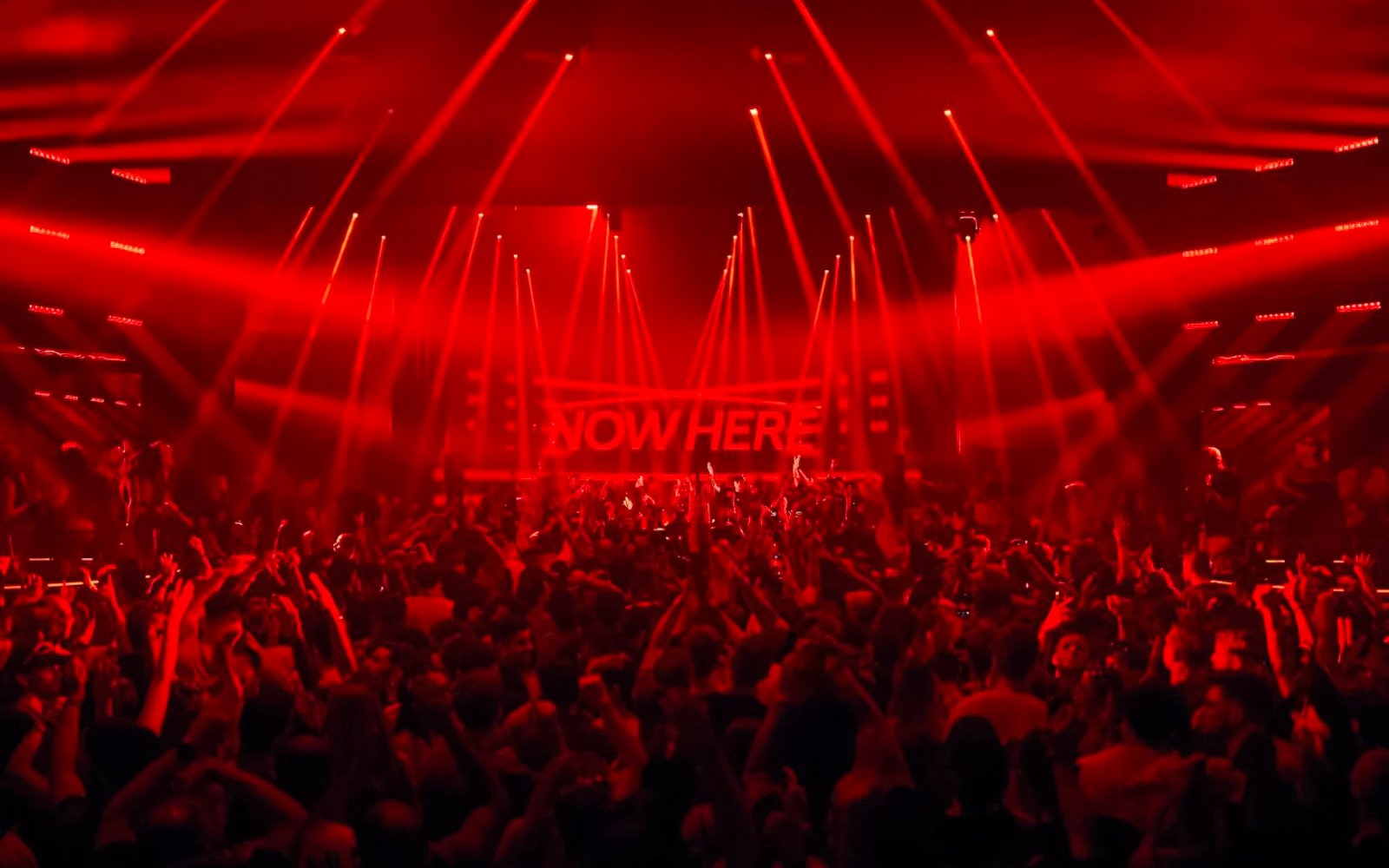 Crowd enjoying Eastenderz performance with red lights in Ibiza nightclub.