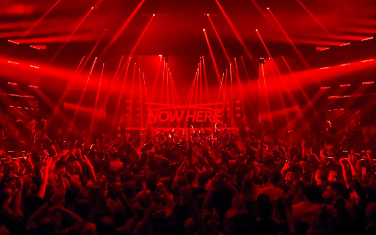 Crowd enjoying Eastenderz performance with red lights in Ibiza nightclub.