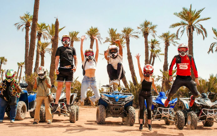Group jumping in front of quad bikes during Palmeraie sunset tour.