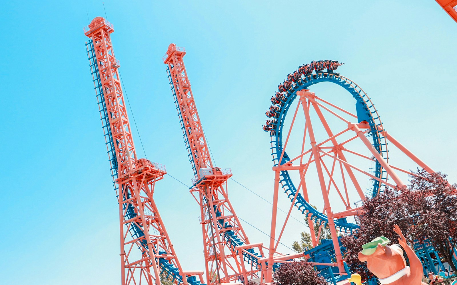 Parque Warner Madrid roller coaster with vibrant cartoon character statues.