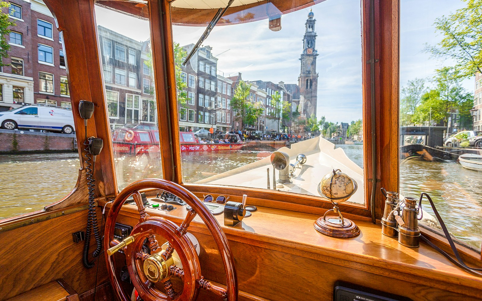 Steering wheel and interior view from an Amsterdam canal cruise boat with Westerkerk in the background.
