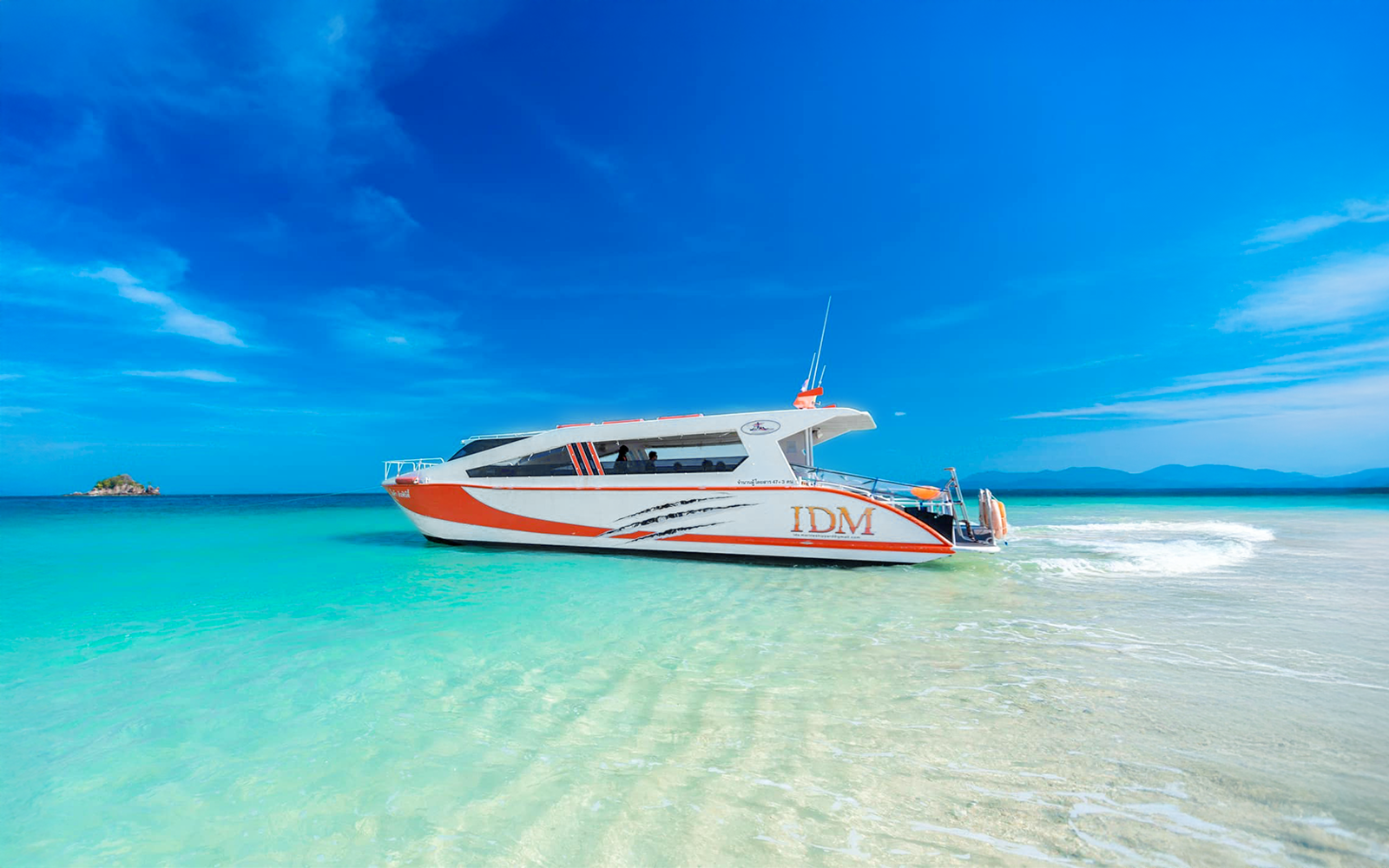 Speedboat on clear water near Phuket, Thailand with distant islands.