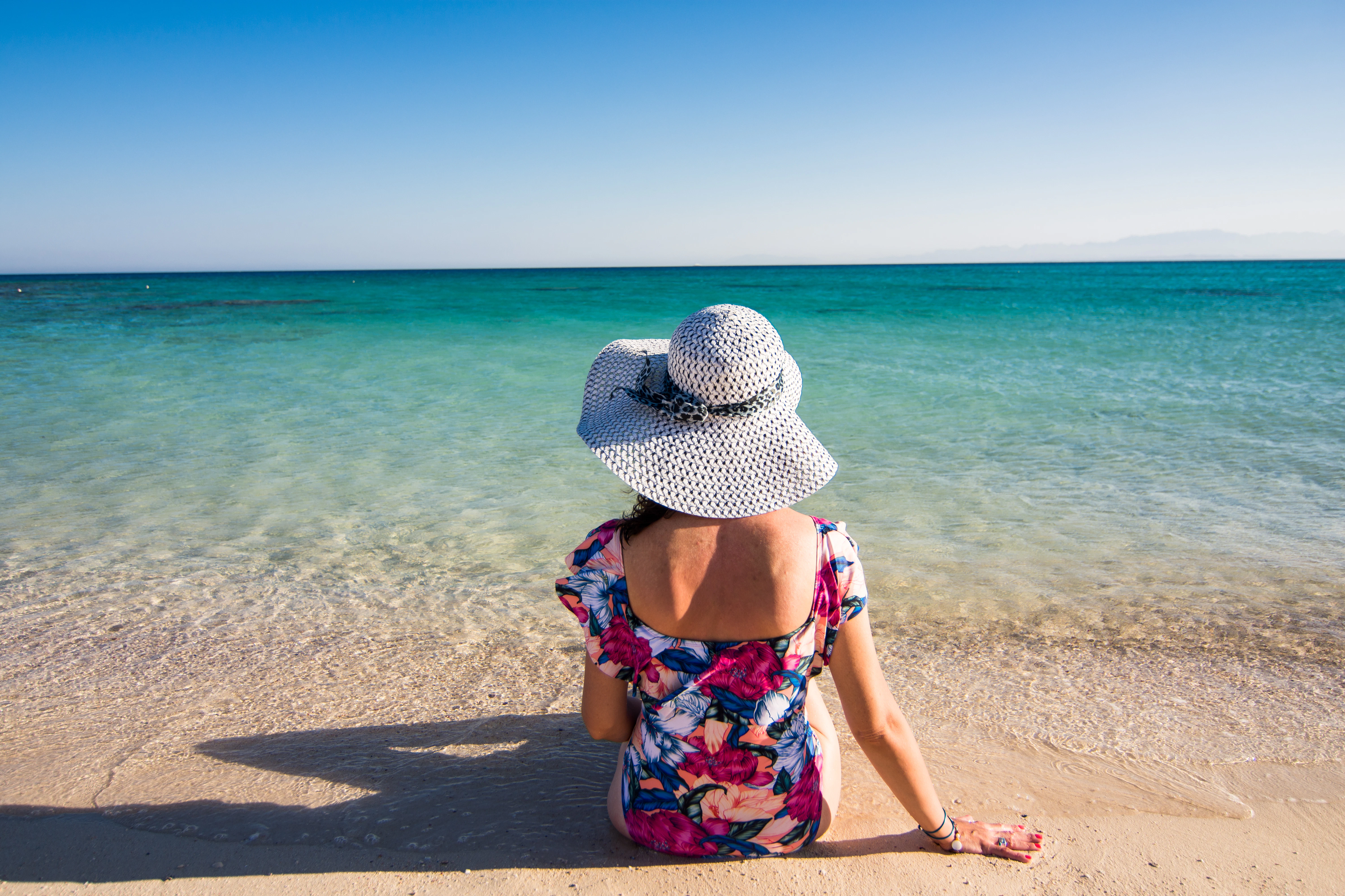 Woman relaxing on Giftun Island beach, Hurghada, facing the sea.