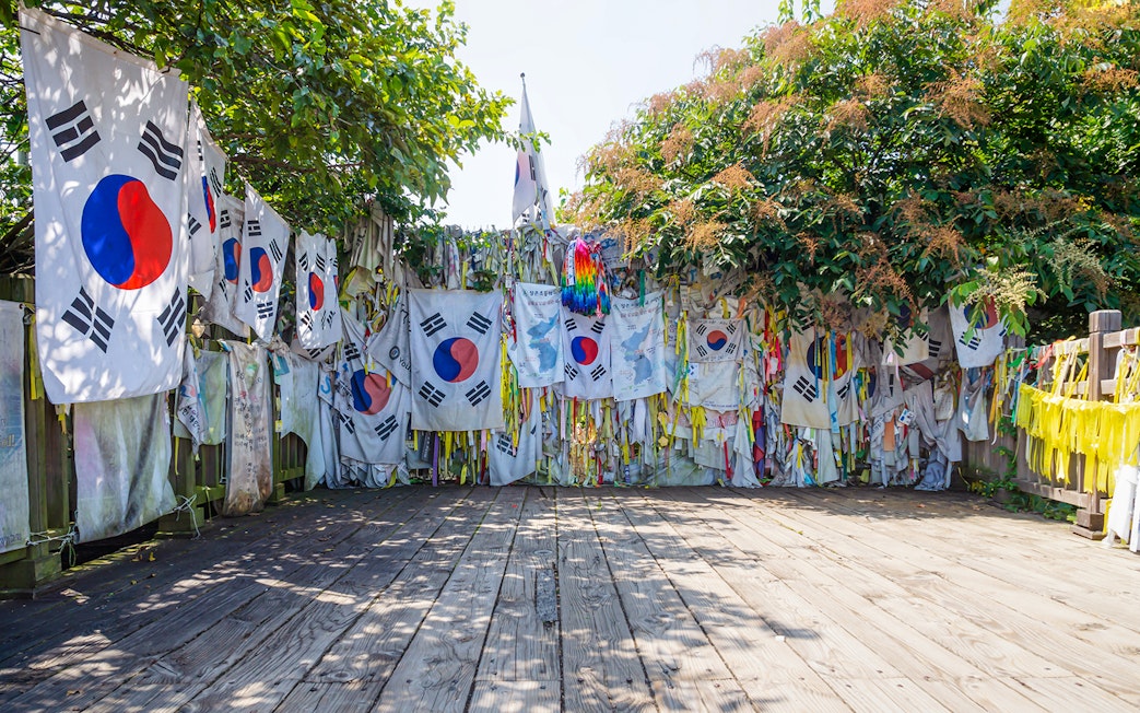 Flags displayed on Freedom Bridge, DMZ, South Korea, surrounded by trees and wooden walkway.