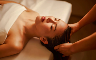 Tourist receiving a warm oil head massage in a spa setting.
