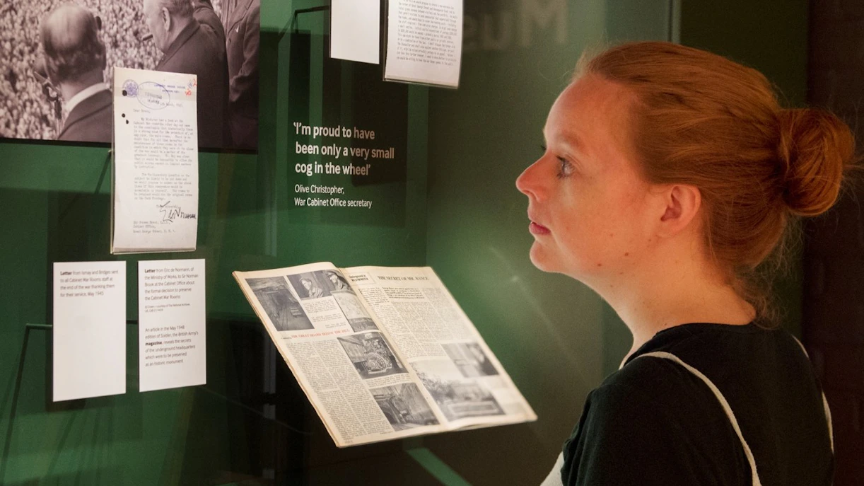 Visitor reading historical documents at Churchill War Rooms museum exhibit.