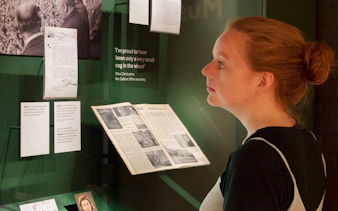 Visitor reading historical documents at Churchill War Rooms museum exhibit.