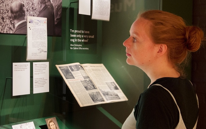 Visitor reading historical documents at Churchill War Rooms museum exhibit.