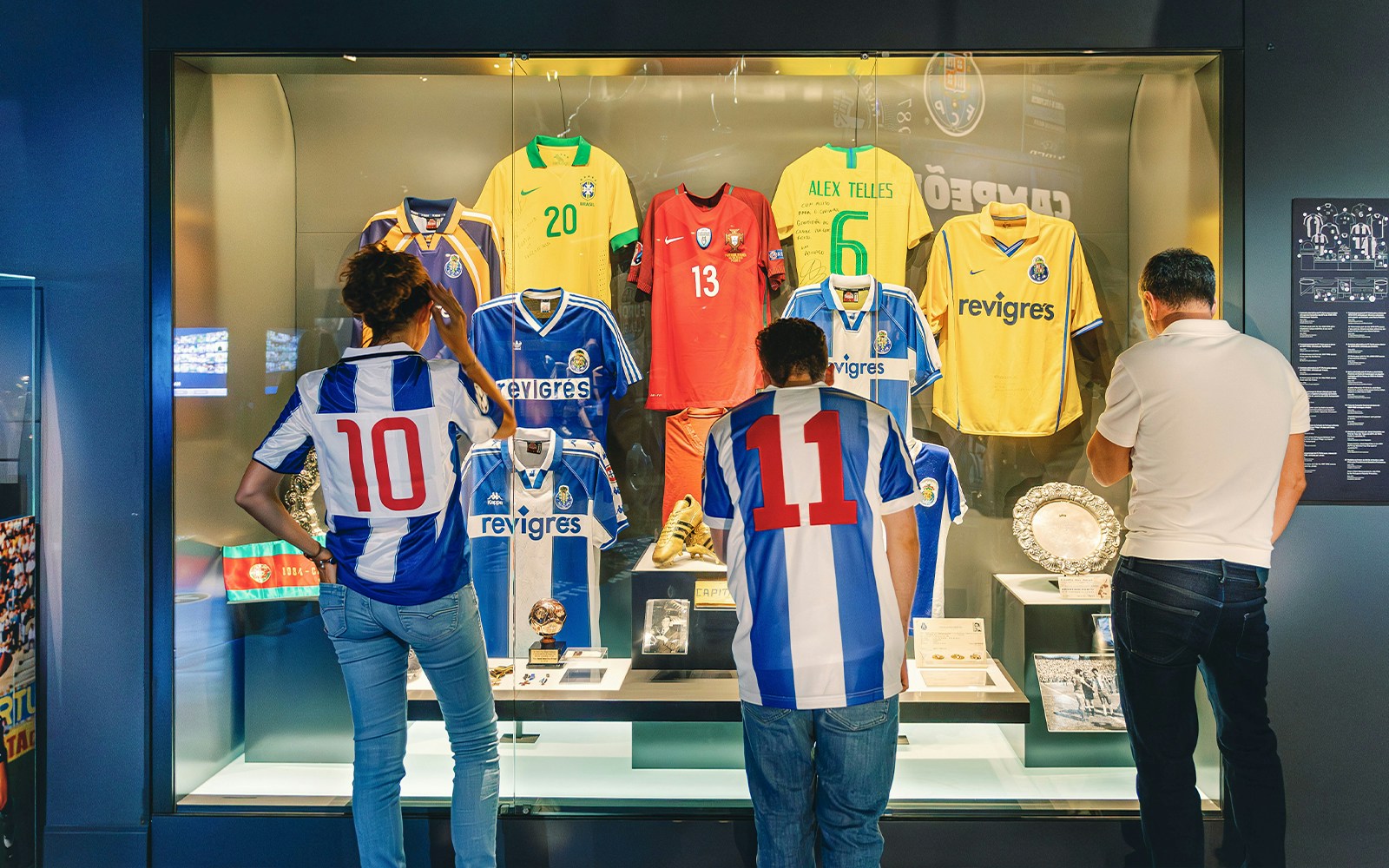 Visitors examining FC Porto stadium museum jerseys display.