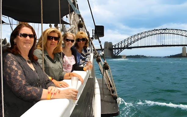 Women on a tall ship cruise in Sydney Harbour with Harbour Bridge in the background.