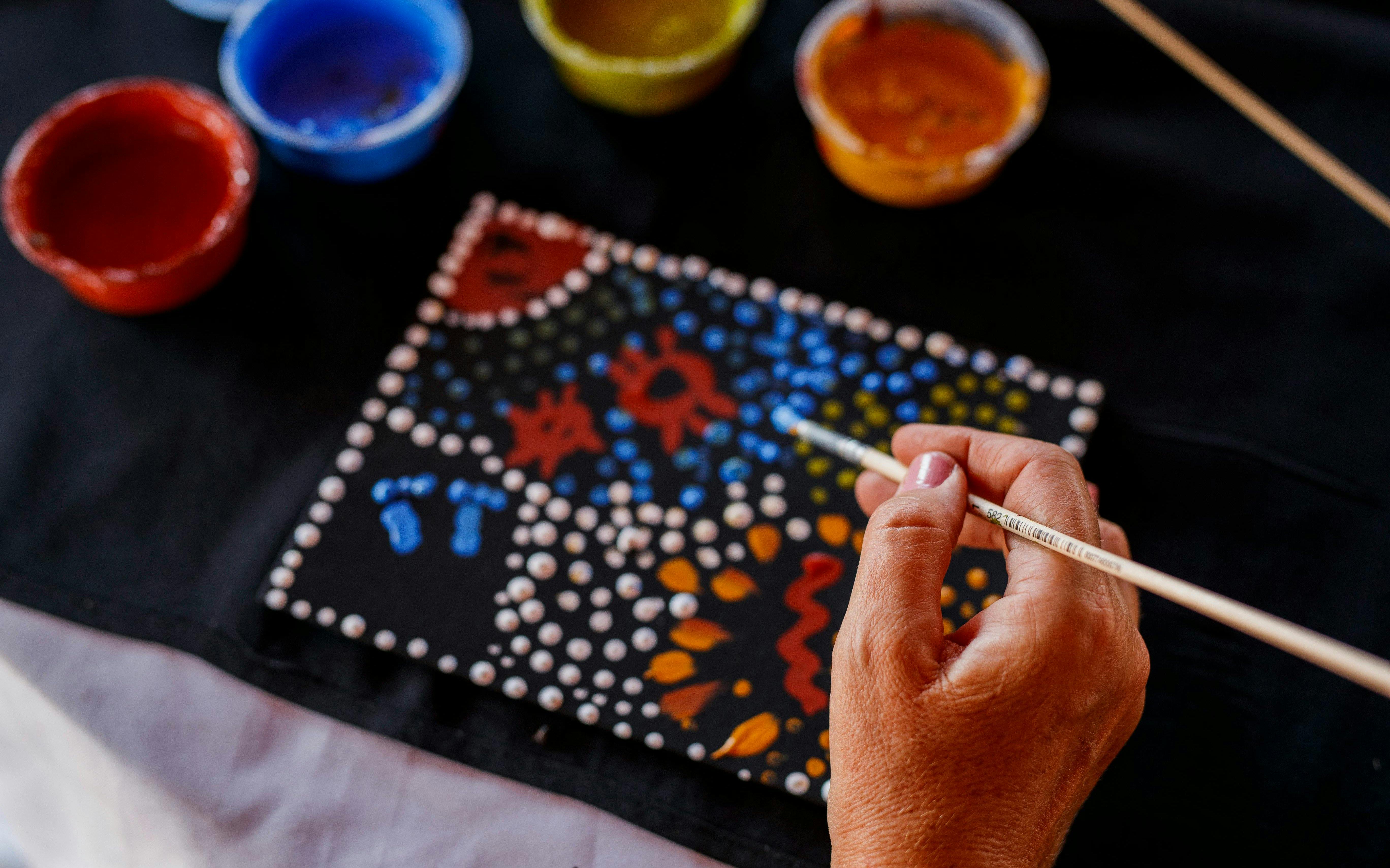 Aboriginal dot painting in progress during Uluru sunrise tour with cultural stories.