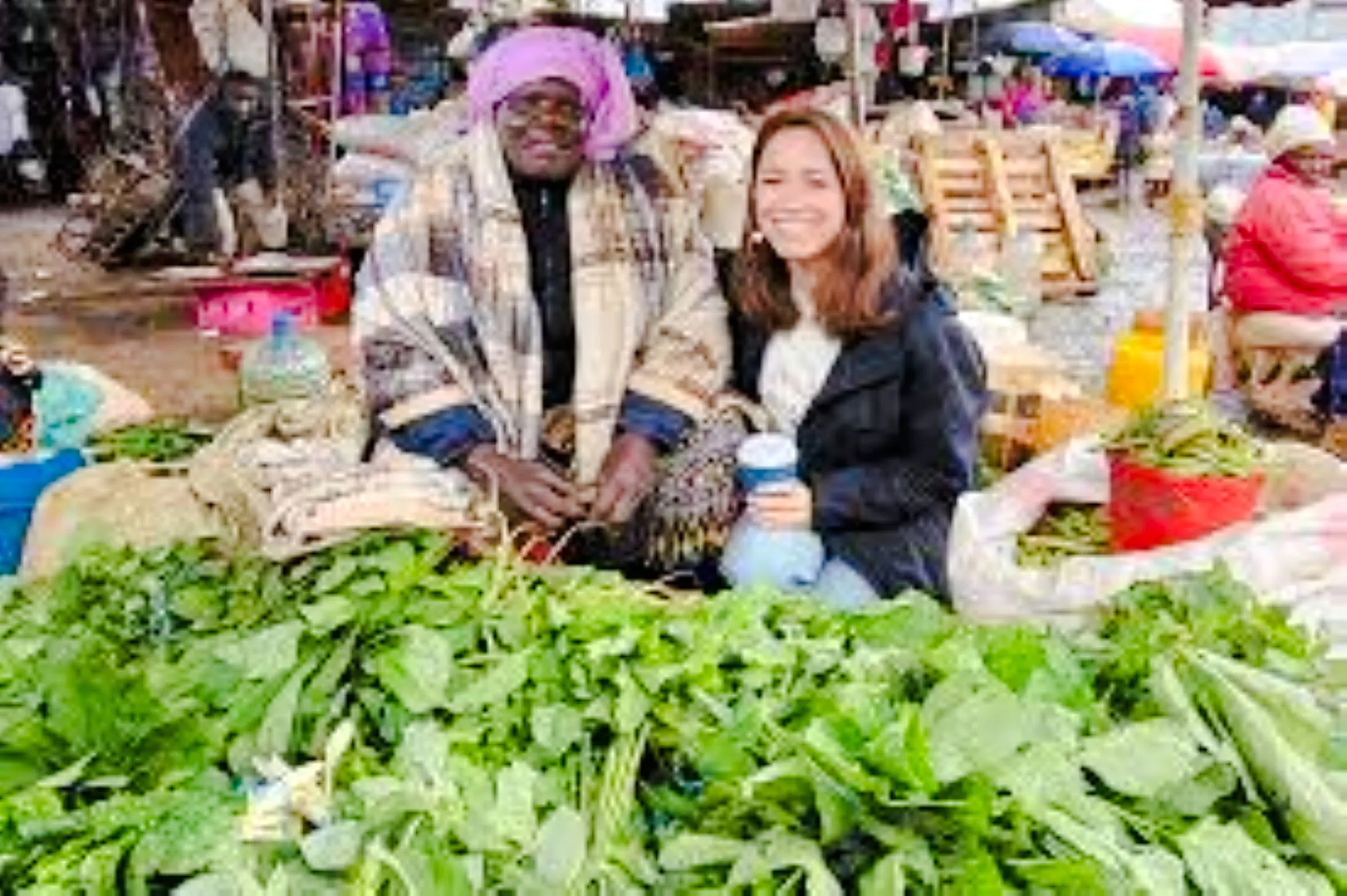 Market vendor and visitor with fresh greens at Nairobi market.