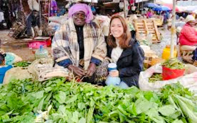 Market vendor and visitor with fresh greens at Nairobi market.