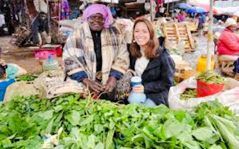 Market vendor and visitor with fresh greens at Nairobi market.