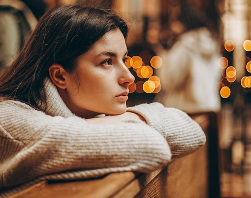 Person sitting in Canterbury Cathedral during Christmas service, with blurred lights in the background.