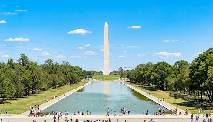 Washington Monument and Reflecting Pool in Washington DC with visitors walking nearby.