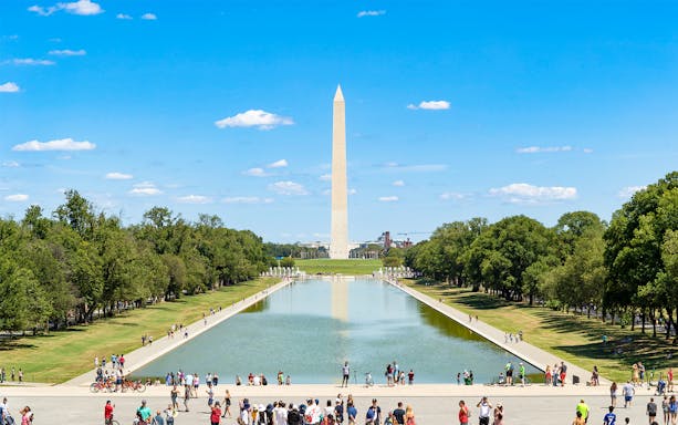 Washington Monument and Reflecting Pool in Washington DC with visitors walking nearby.