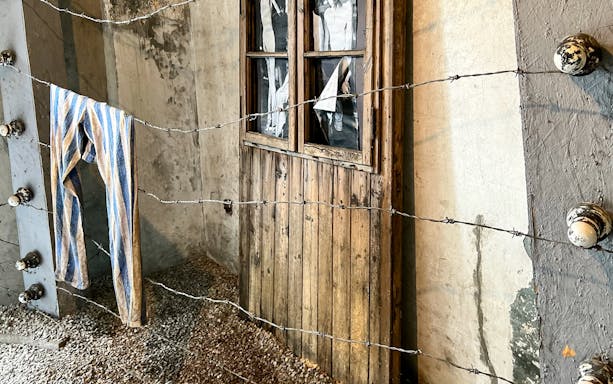 Barbed wire fence and striped clothing at Auschwitz sub-camp exhibit.