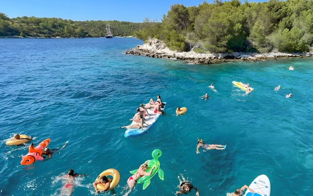 People enjoying a swim and paddleboarding near Hvar during a Split islands cruise.