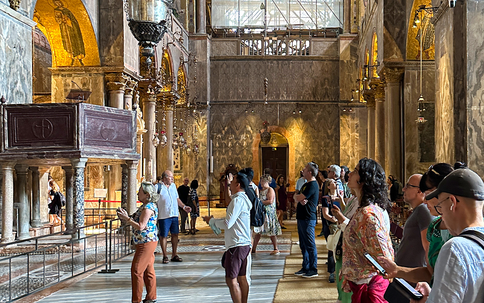 Visitors inside St. Mark's Basilica, Venice, using audioguides to explore the ornate interior.