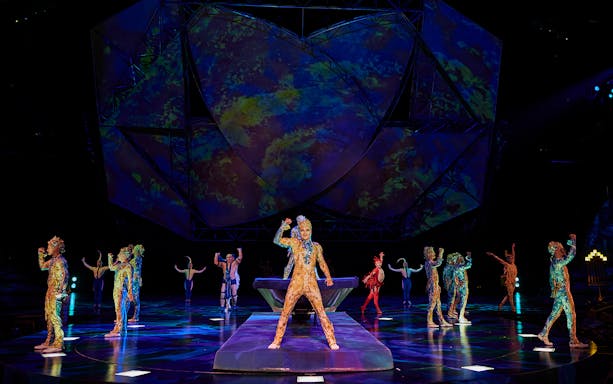 Performers in colorful costumes on stage during Mystère show.
