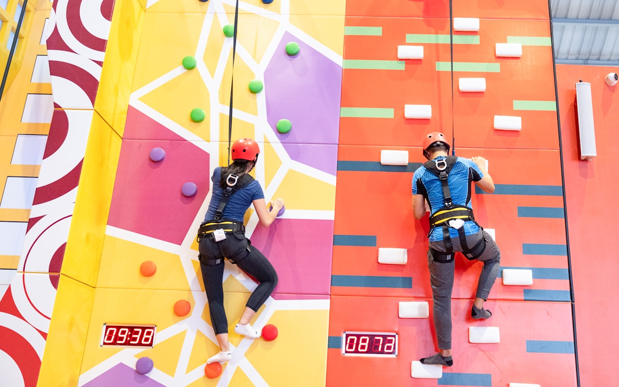 Man and woman climbing colorful indoor rock wall.