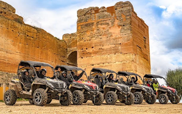Guided buggy tour group in Albufeira, Portugal, parked by ancient ruins.