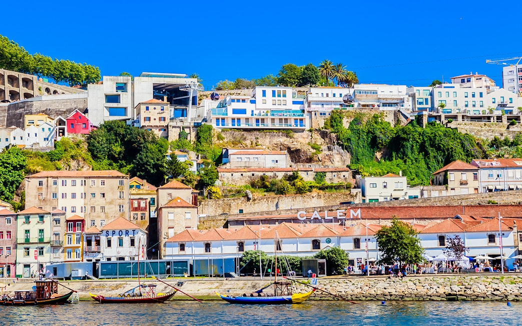 Cálem Cellars in Porto with colorful hillside buildings and traditional boats on the Douro River.