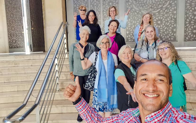 Group of tourists smiling on steps inside Hassan II Mosque, Casablanca, Morocco.