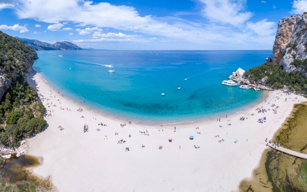 Aerial view of Cala Luna beach with boats in the Gulf of Orosei, Italy.