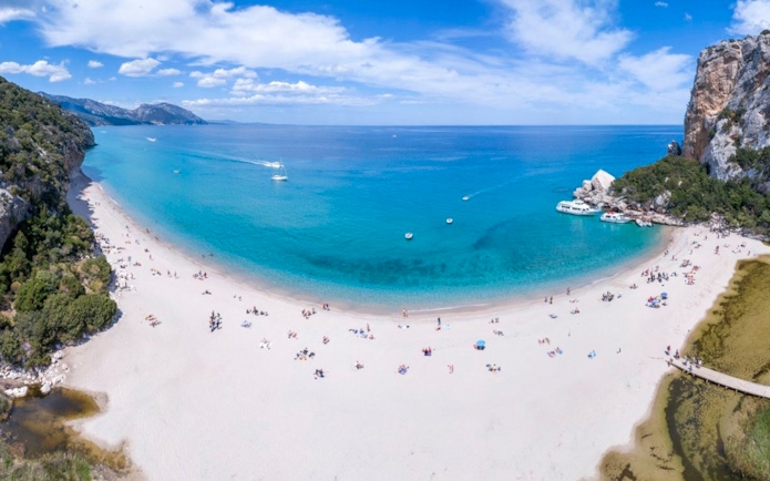 Aerial view of Cala Luna beach with boats in the Gulf of Orosei, Italy.