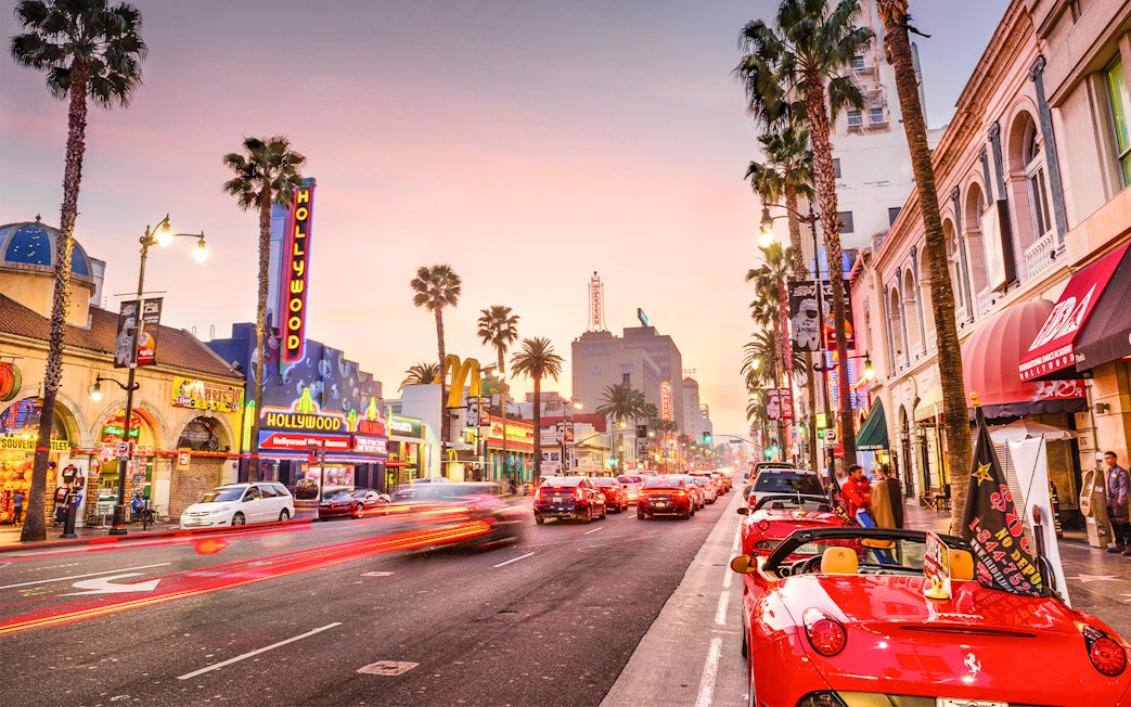 Hollywood Boulevard at sunset with neon signs and palm trees, part of TMZ Hollywood Tour.