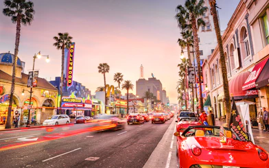 Hollywood Boulevard at sunset with neon signs and palm trees, part of TMZ Hollywood Tour.