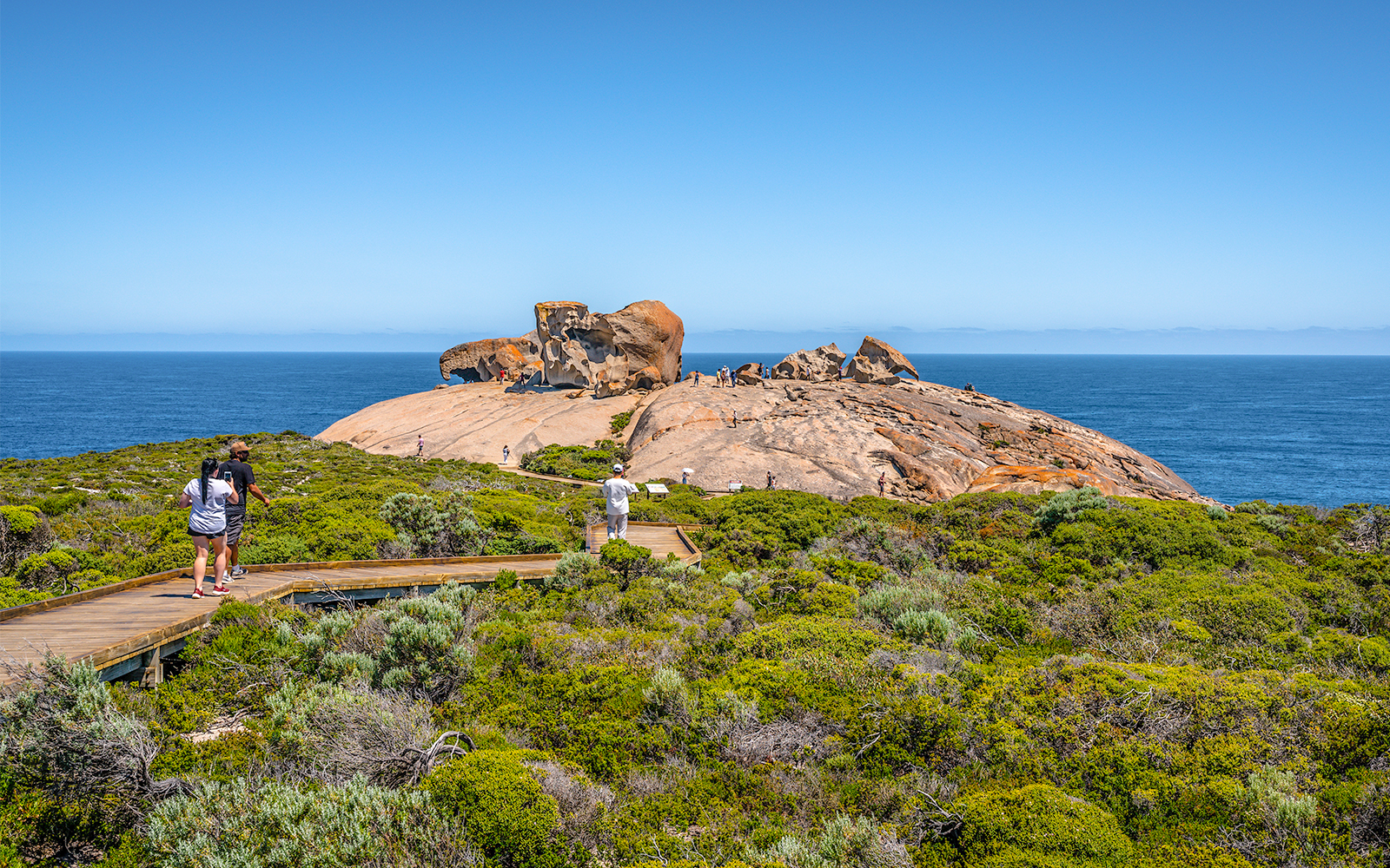 Remarkable Rocks on Kangaroo Island with tourists walking on a boardwalk, ocean in the background.