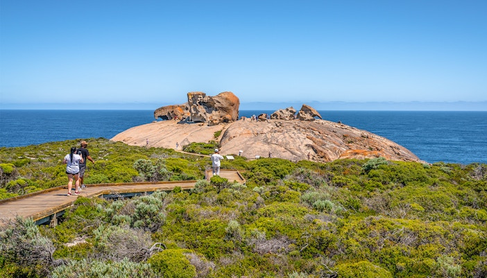 Remarkable Rocks on Kangaroo Island with tourists walking on a boardwalk, ocean in the background.
