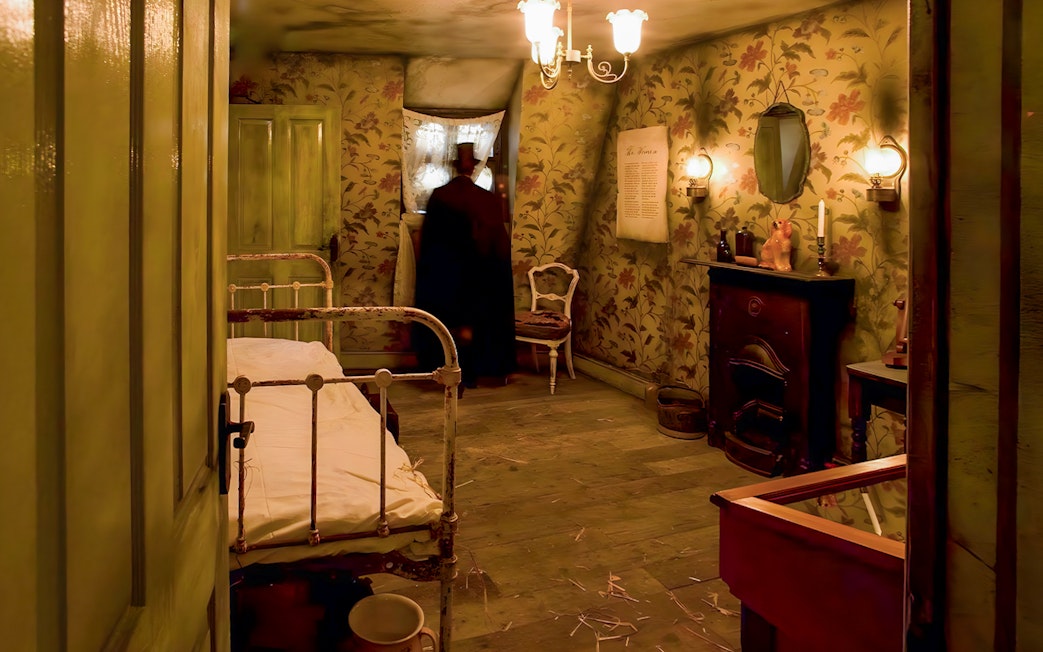 Victorian-style room in Jack the Ripper Museum with bed, fireplace, and figure by window.