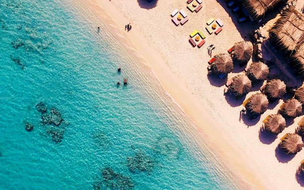 Snorkelers in clear waters near beach huts on Paradise Island, Hurghada.