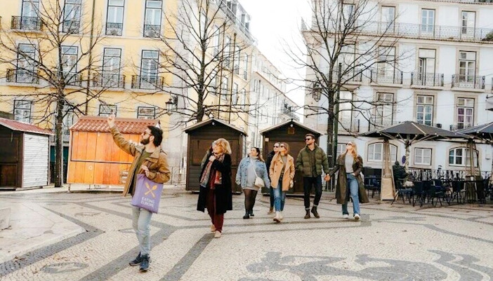 Tour group with guide sampling local cuisine in Lisbon street market.