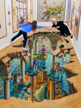 Visitors interacting with 3D floor art at IAM Illusion Art Museum, Prague.