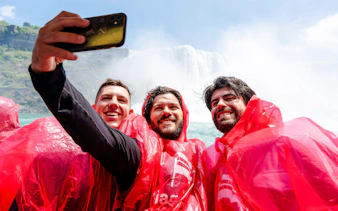 Tourists in red ponchos taking a selfie on a Niagara Falls boat cruise.