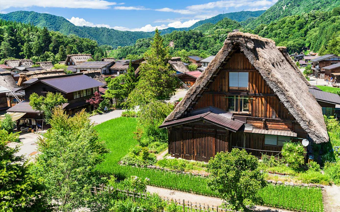 Traditional gassho-style houses in Shirakawa-go village, surrounded by lush greenery, on a day tour from Kanazawa.