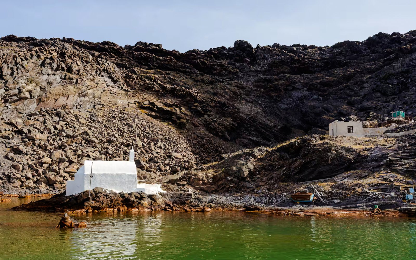 White chapel and rocky landscape at Palea Kameni, Santorini caldera, Greece.