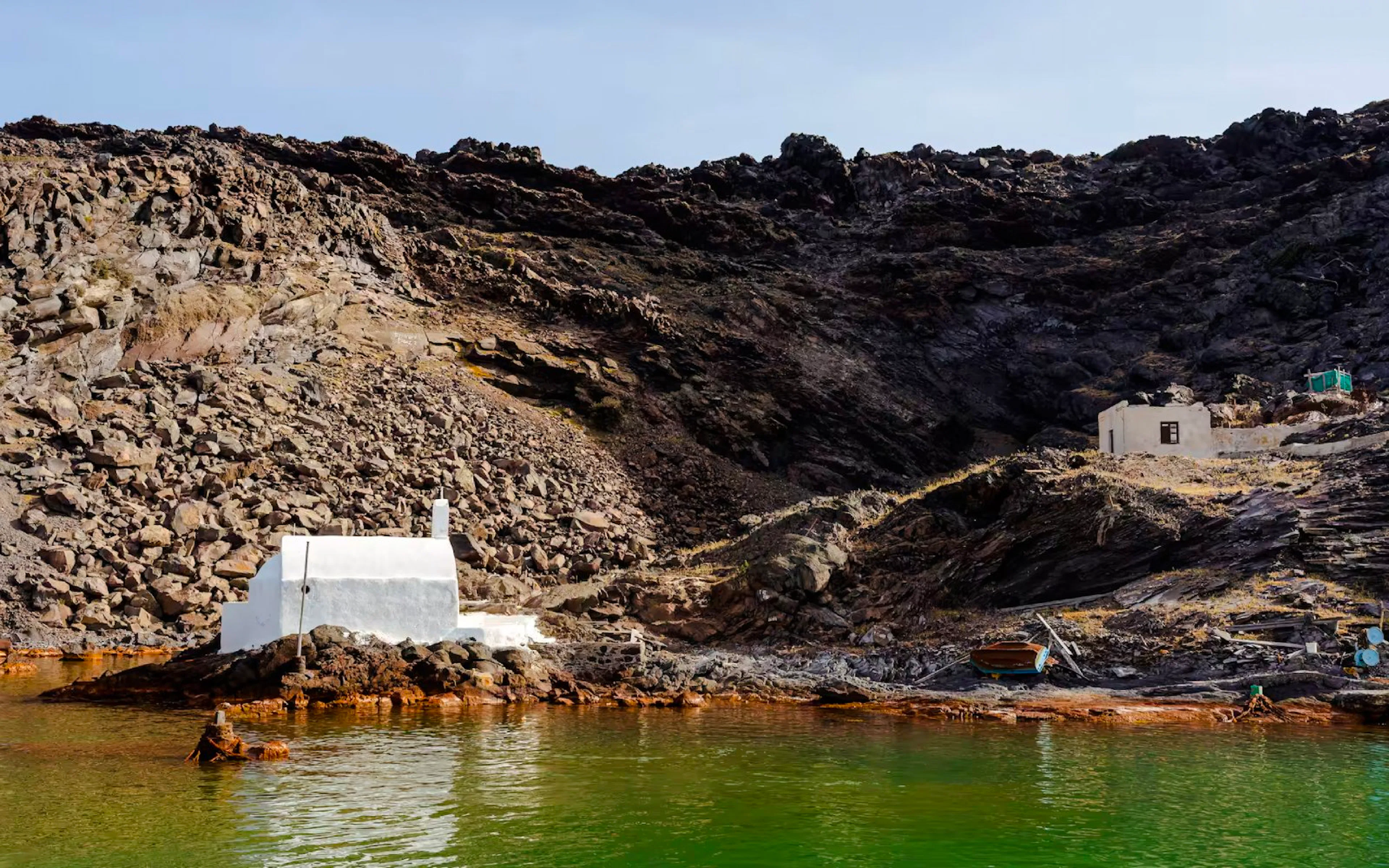 White chapel and rocky landscape at Palea Kameni, Santorini caldera, Greece.