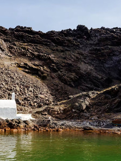 White chapel and rocky landscape at Palea Kameni, Santorini caldera, Greece.