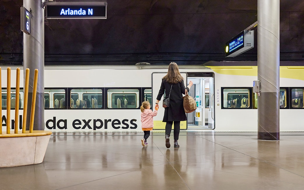 Woman and daughter boarding Arlanda Express train at Stockholm station.