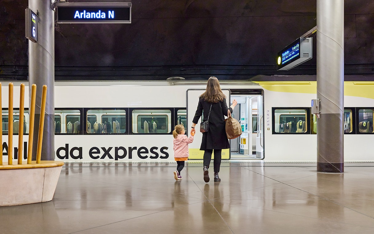 Woman and daughter boarding Arlanda Express train at Stockholm station.