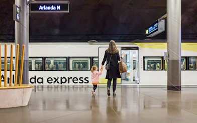 Woman and daughter boarding Arlanda Express train at Stockholm station.