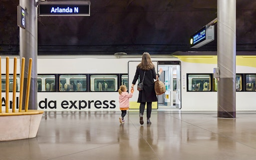Woman and daughter boarding Arlanda Express train at Stockholm station.