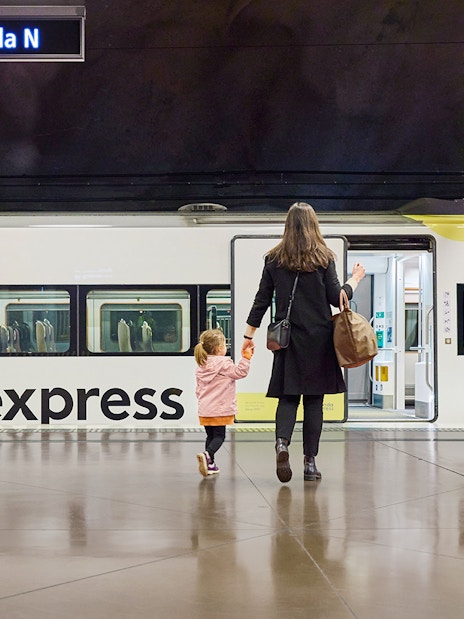 Woman and daughter boarding Arlanda Express train at Stockholm station.