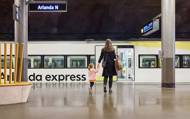 Woman and daughter boarding Arlanda Express train at Stockholm station.